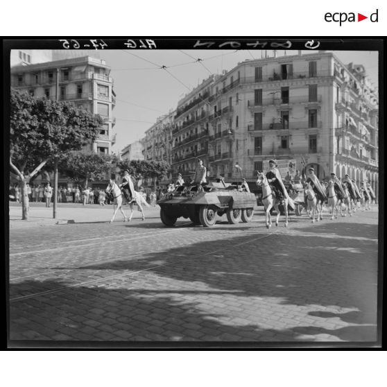 Le général Schlesser défile à bord d'un véhicule blindé, suivi par une unité de spahis.