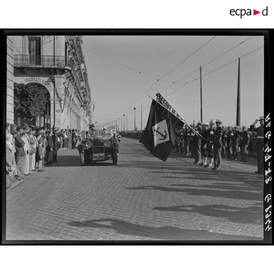 Des autorités militaires défilent en voiture, sous le regard de la population civile.