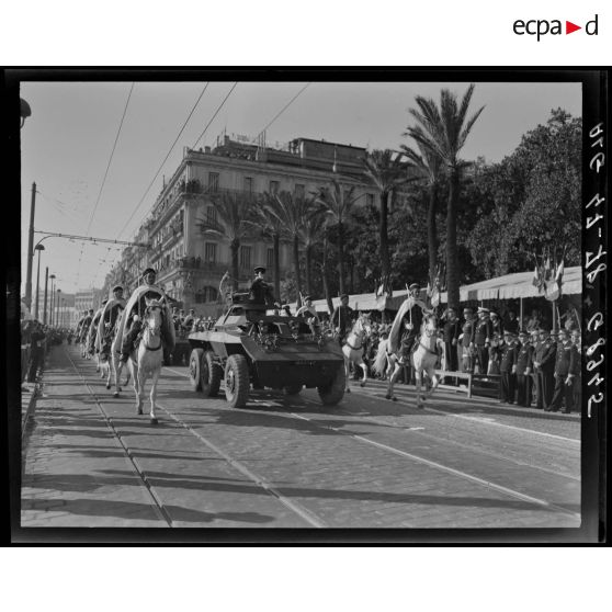 Le général Schlesser défile à bord d'un véhicule blindé, sous le regard d'autorités militaires, accompagné d'une unité de spahis.