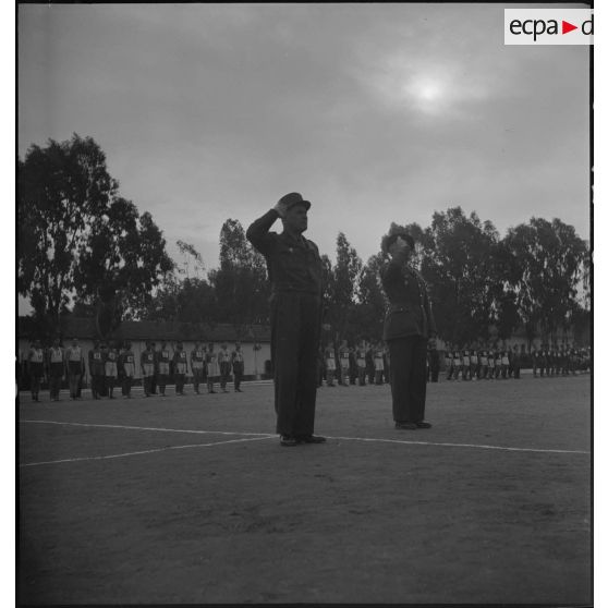 Le général Duché salue le drapeau, accompagné d'une autorité militaire, sur un stade.