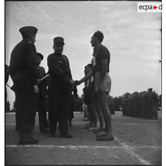 Le général Duché salue les participants au championnat militaire sportif, accompagné d'autorités militaires.