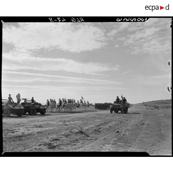 Une autorité militaire passe en revue des troupes, à bord d'un véhicule blindé.