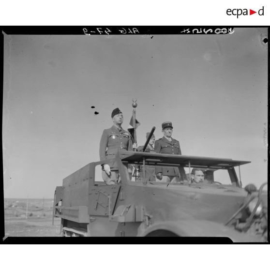 Plan rapproché du général de division André Kientz, qui passe en revue des troupes, à bord d'un véhicule blindé.