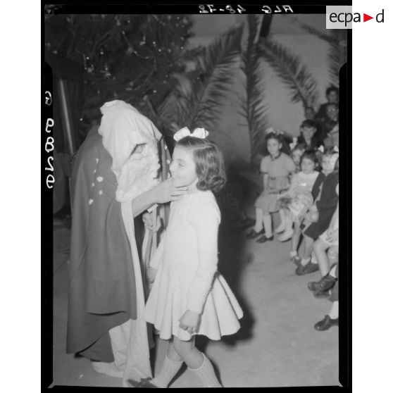 Le Père Noël s'adresse à une fillette, lors de la fête de Noël des enfants de militaires en Algérie.