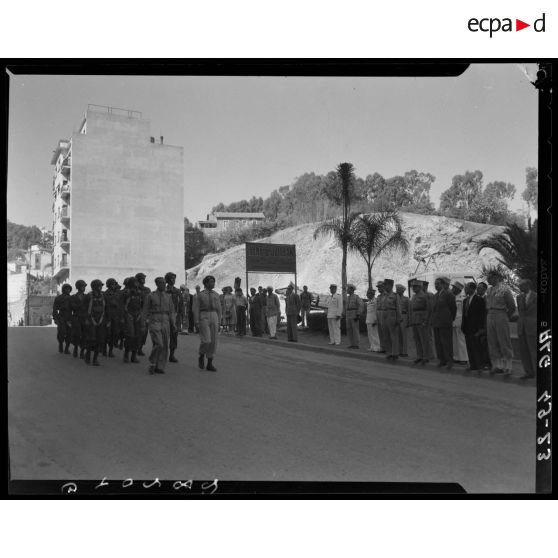 Défilé d'une unité militaire, sous le regard d'autorités civiles et militaires.