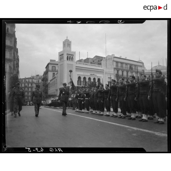 Le général Georges Catroux passe les troupes en revue, à Alger, devant le bâtiment du journal Alger républicain.