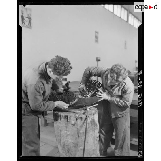 Deux élèves de l'Ecole de l'Air de Cap Matifou, s'exercent à travailler sur une pièce d'avion, dans un atelier.