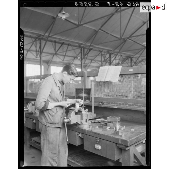 Un élève de l'Ecole de l'Air de Cap Matifou travaille sur une pièce d'avion dans un atelier.