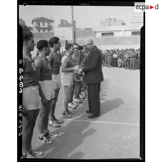 Une personnalité civile remet la coupe aux gagnant d'un match de basket-ball lors des championnats militaires interarmes d'Alger.