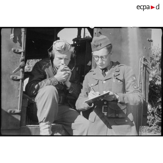 A l'aide d'un émetteur-récepteur radio, deux soldats transmettent et notent des données.