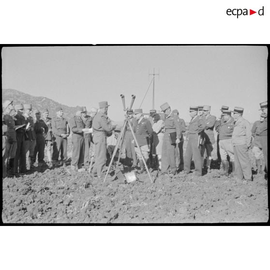 Des personnalités militaires sont rassemblées autour d'un télémètre, afin d'observer le déroulement de la manoeuvre.