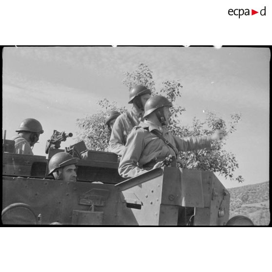 Plan rapproché des soldats à bord d'un Bren Carrier, blindé de reconnaissance, en pleine mission.