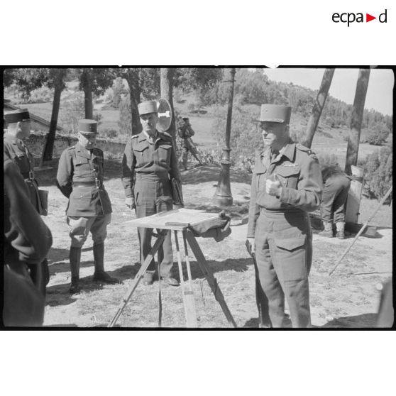 Des personnalités militaires sont rassemblées autour du plan de manoeuvre en cours.