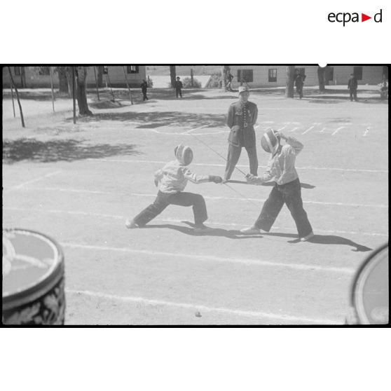 Deux élèves de l'école militaire préparatoire nord-africaine (EMPNA) d'Hammam Righa pratiquent l'escrime, sous le regard de personnalités militaires.