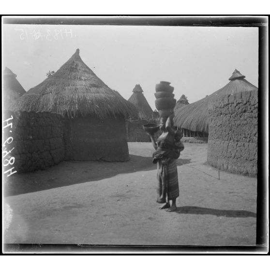 N'Gaoundéré village. Une emme portant 10 calebasses sur sa tête. [légende d'origine]