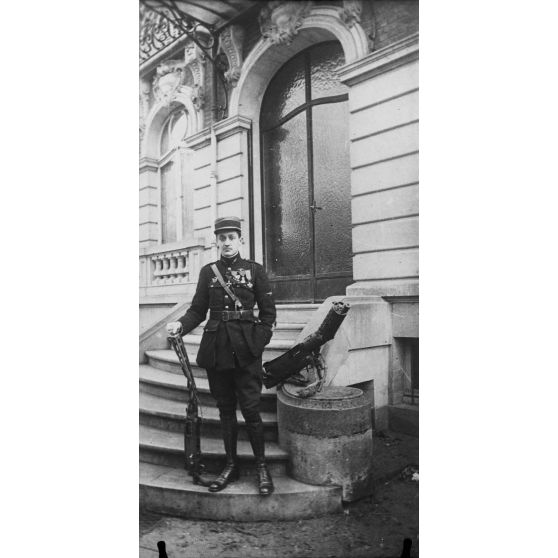 Un officier pose devant l'entrée d'un bâtiment. [légende d'origine]