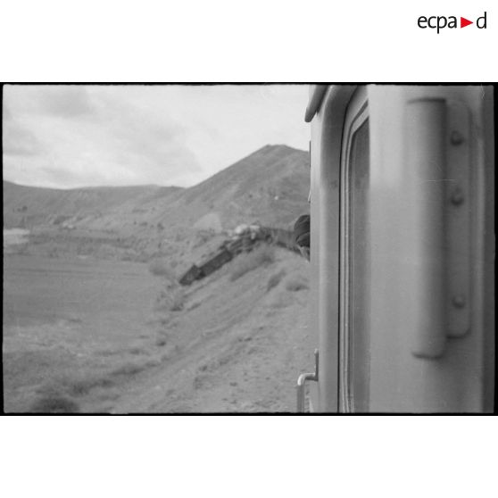 Vue du train qui a déraillé sur le bas-côté de la voie ferrée. [légende d'origine]