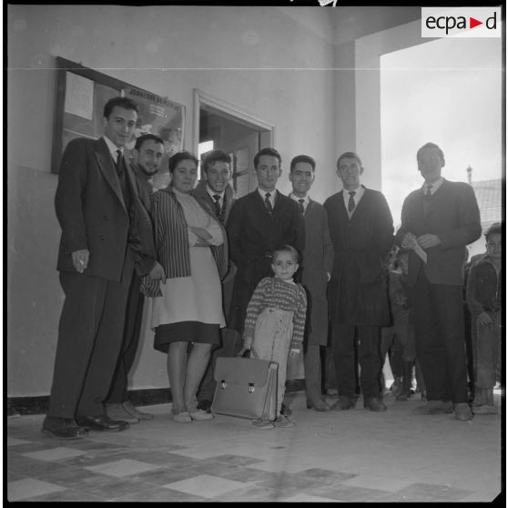 Portrait de groupe du corps enseignant d'un établissement scolaire. Plusieurs jeunes enfants sont également visibles à l'image. [légende d'origine]
