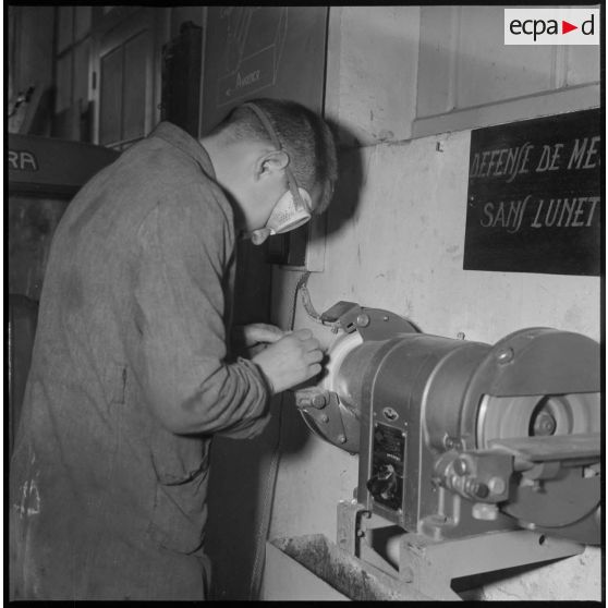 Apprentissage professionnel. Un élève meule une pièce. [légende d'origine]