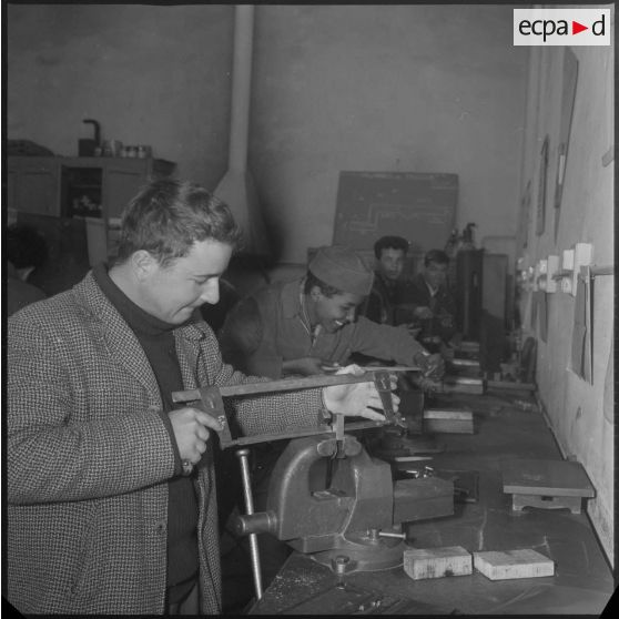 Apprentissage professionnel. A l'aide d'une scie à métaux, des élèves travaillent des pièces métalliques bloquées dans des étaux. [légende d'origine]