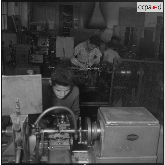 Apprentissage professionnel. Élèves derrière un poste d'ajustage ou de filetage. [légende d'origine]