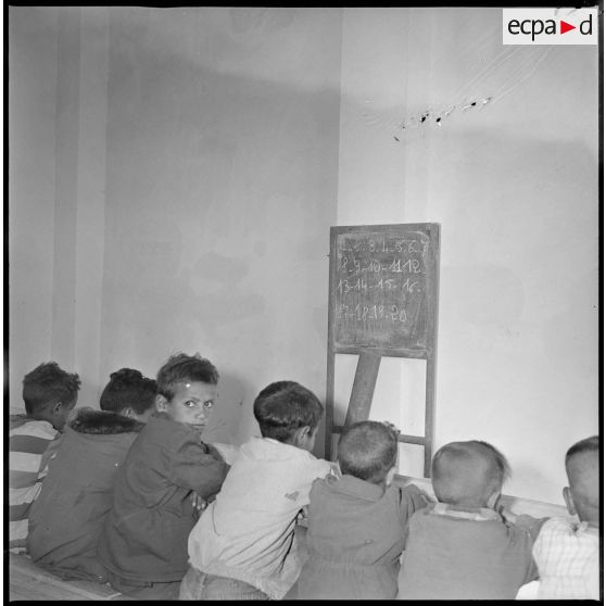 De jeunes écoliers apprennent à compter et à lire les chiffres de 1 à 20 inscrits sur le tableau devant eux. [légende d'origine]