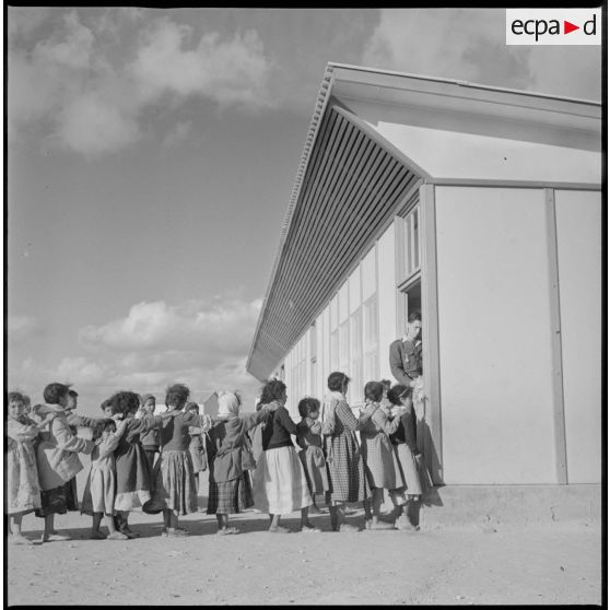 Elèves en rang devant l'entrée de leur salle de classe. [légende d'origine]
