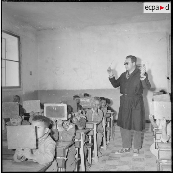 Les élèves répondent à leur professeur en indiquant sur leurs ardoises le nombre de crayons que celui-ci tient dans les mains. [légende d'origine]