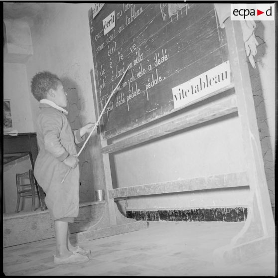 Un jeune écolier lit les phrases inscrites au tableau de sa classe. [légende d'origine]