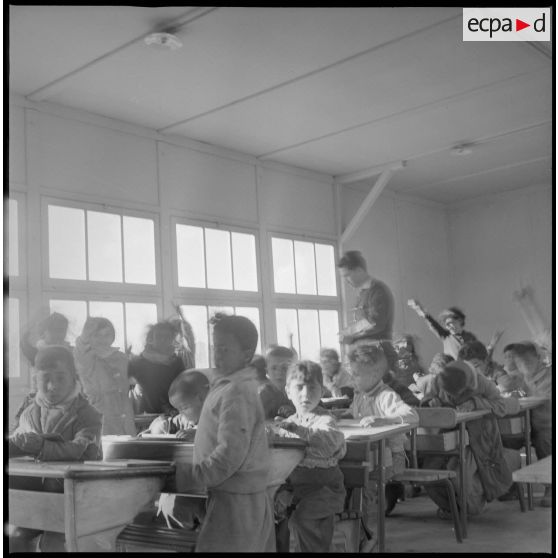 Dans une salle de classe mixte, un professeur interroge ses jeunes écolières. [légende d'origine]