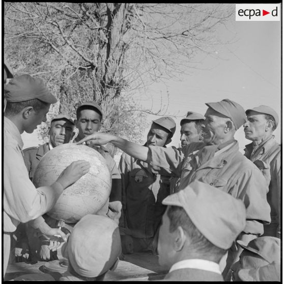 Plusieurs membres du commando Cobra sont rassemblés autour d'un globe terrestre et écoutent attentivement les observations qui leurs sont faites. [légende d'origine]