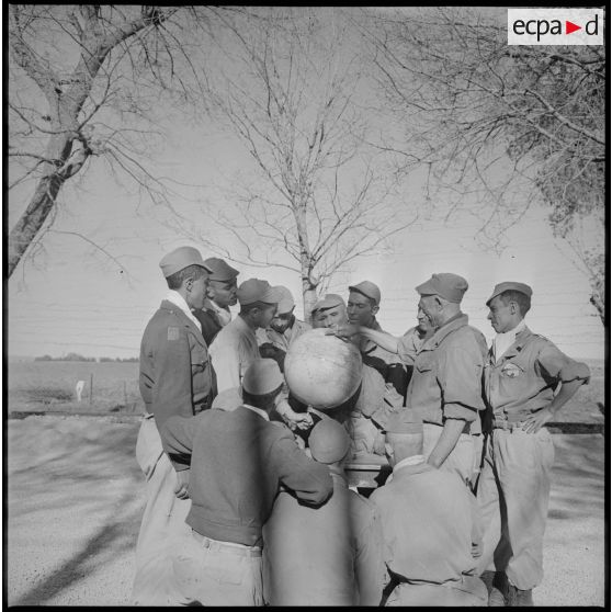 Plusieurs membres du commando Cobra sont rassemblés autour d'un globe terrestre et écoutent attentivement les observations qui leurs sont faites. [légende d'origine]