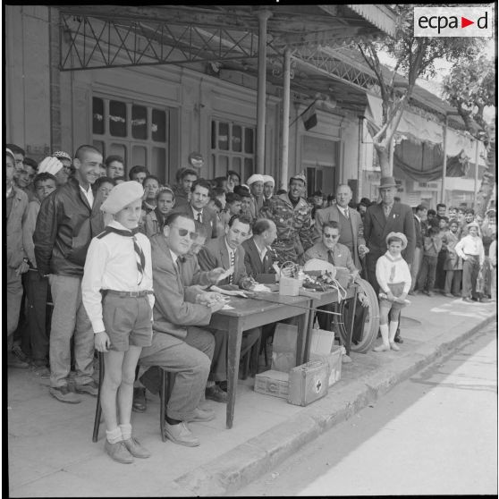 Course cycliste à Saïda. Les juges installés à l'arrivée de la course. Deux jeunes scouts sont visibles. [légende d'origine]