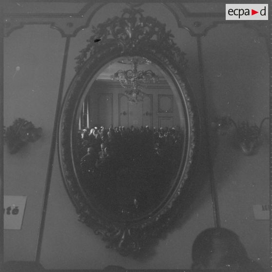 A l'Hôtel de ville de Saïda, vues d'un miroir dans lequel se reflètent les personnalités rassemblées à l'occasion de la visite du Délégué général du gouvernement en Algérie Paul Delouvrier. [légende d'origine]