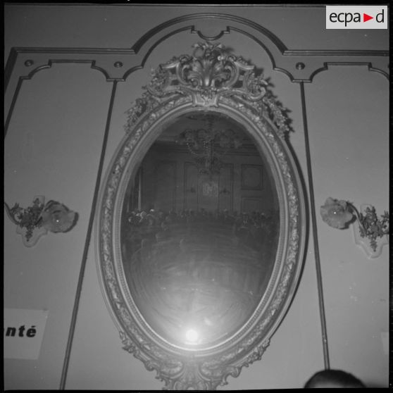 A l'Hôtel de ville de Saïda, vues d'un miroir dans lequel se reflètent les personnalités rassemblées à l'occasion de la visite du Délégué général du gouvernement en Algérie Paul Delouvrier. [légende d'origine]