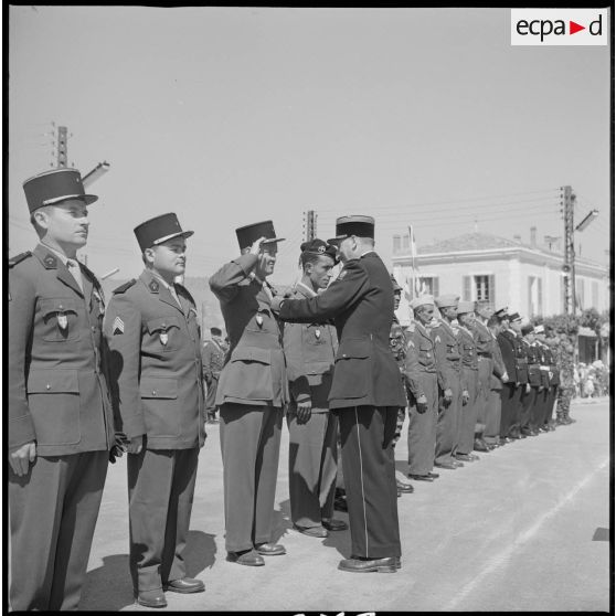 Le colonel le Demetz remet une décoration à un soldat. Le récipiendaire salue. [légende d'origine]