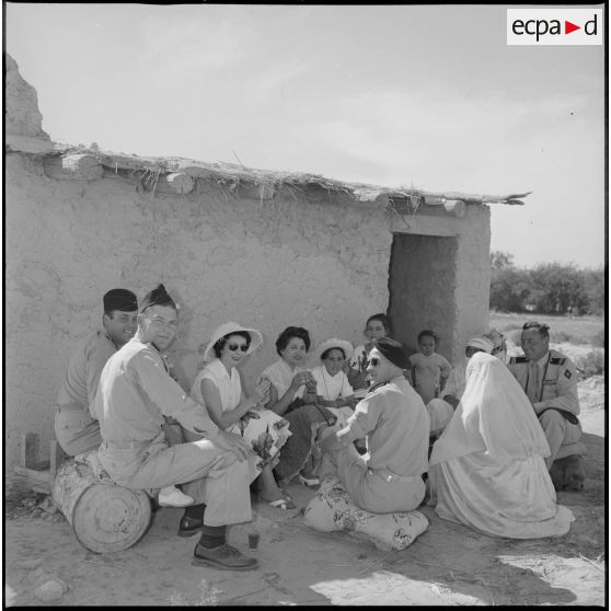 A l'occasion de la visite d'un village, des officiers boivent le thé devant une maison. [légende d'origine]