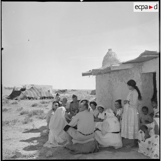 A l'occasion de la visite d'un village, des officiers boivent le thé devant une maison. [légende d'origine]