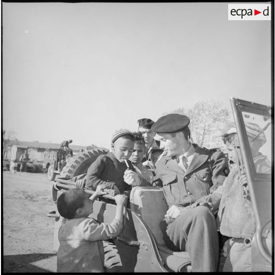 Un soldat allume la cigarette d'un jeune garçon du village. [légende d'origine]