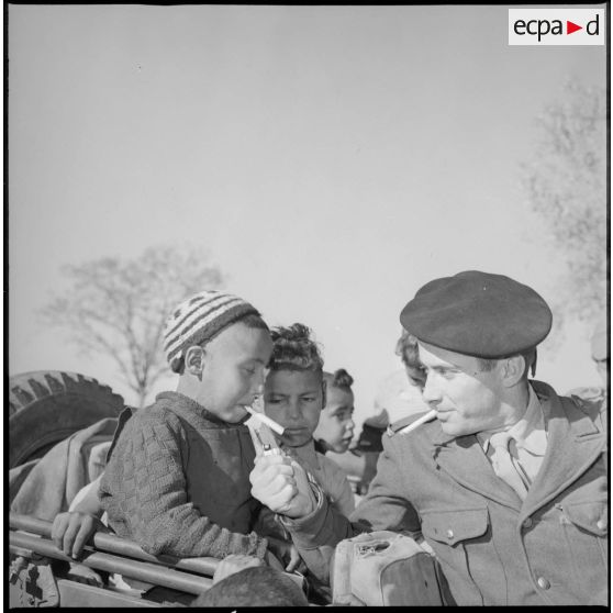 Un soldat allume la cigarette d'un jeune garçon du village. [légende d'origine]