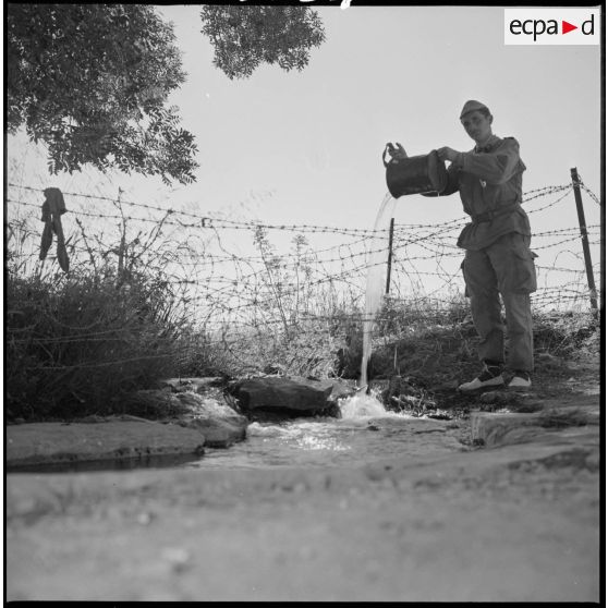 Un soldat vide un seau d'eau dans un ruisseau. [légende d'origine]