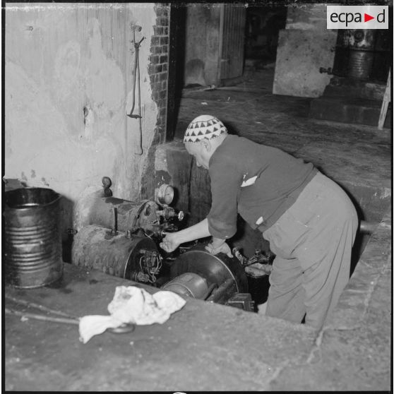 [Papeterie d'Aïn-el-Hadjar. Un ouvrier effectue des réglages sur une machine.]