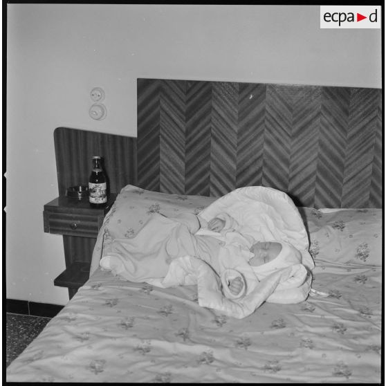 [Nourrisson dormant sur un lit.]