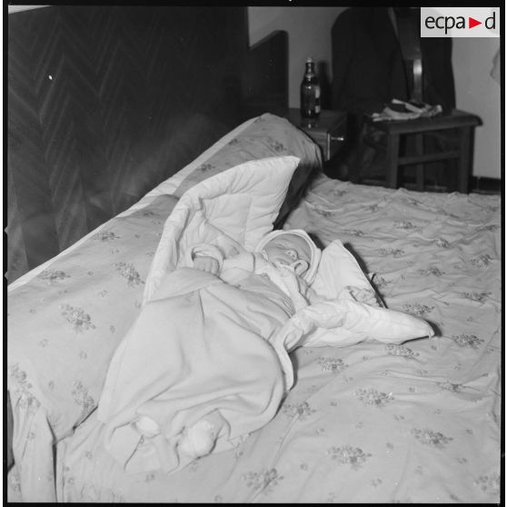 [Nourrisson dormant sur un lit.]