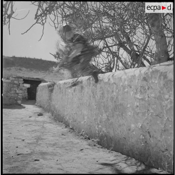 [Entraînement de parachutistes dans le Vieux Saïda. Soldat franchissant un muret.]