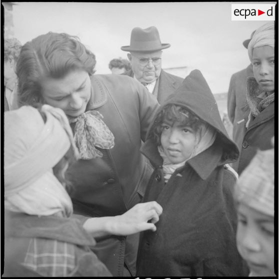 [Poste de Tamesna, région de Saïda. Femme aidant une enfant à mettre un manteau donné à l'occasion d'une action caritative initiée par des Luxembourgeois.]