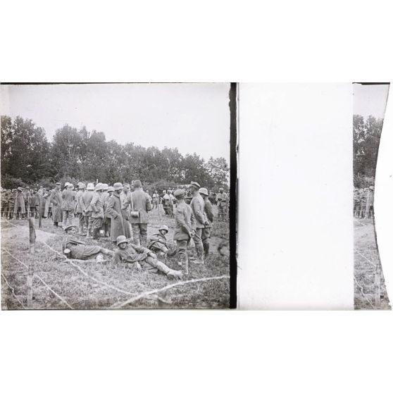[Rassemblement de prisonniers debout et allongés dans l'herbe.]