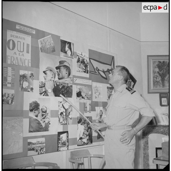 [Le commandant Moisson montrant un panneau photographique dans les locaux du Bureau du moral (BDM) d'Oran.]
