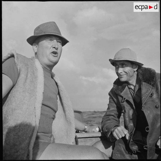 [Discussion entre deux hommes lors d'une partie de pêche près du port d'Oran.]