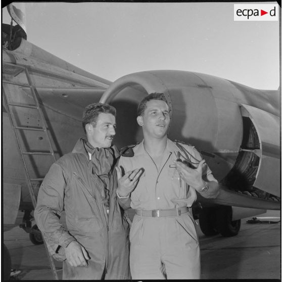 [Pilote de l'armée de l'Air et un soldat posant devant un avion de chasse.]